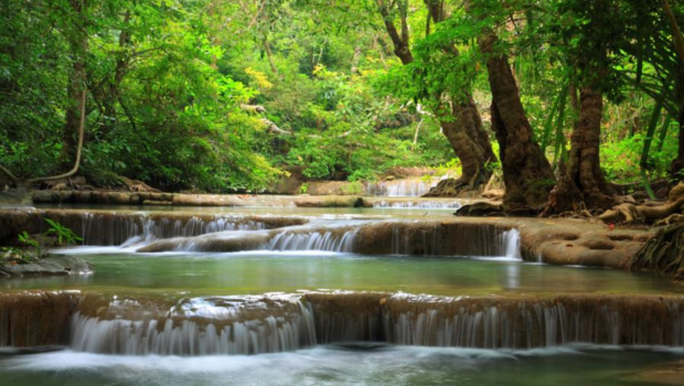 Multi-tiered turquoise pools of Erawan Waterfall surrounded by lush green jungle