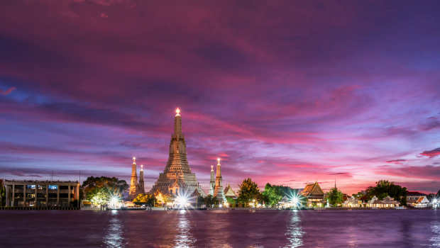 Ancient Thai temple silhouetted against a dramatic purple sky at sunset