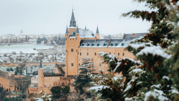 Alcázar of Segovia in Spain covered with light snow, looking like a real-life fairytale fortress.