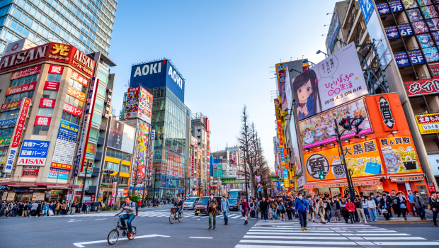 Busy street crossing in Akihabara Tokyo with colourful anime billboards and crowds of people