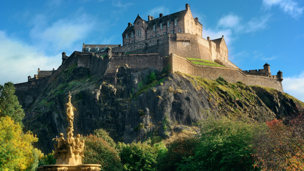Edinburgh Castle perched on an ancient volcanic rock in the heart of Scotland’s capital, surrounded by green trees.