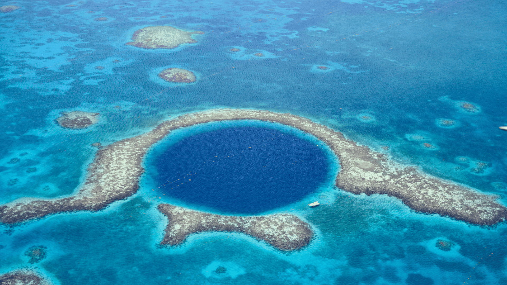 มุมมองทางอากาศของ Great Blue Hole หลุมยุบกลางทะเลสีฟ้าเข้มล้อมด้วยแนวปะการัง