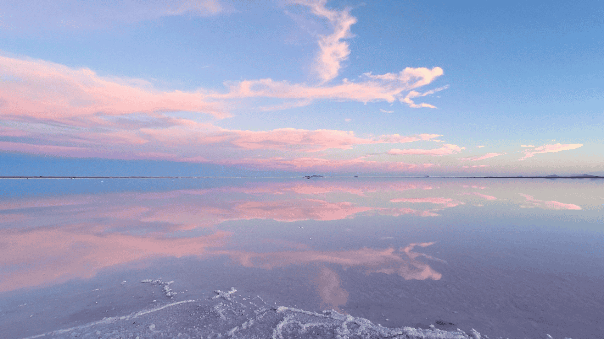 ภาพสะท้อนท้องฟ้าสีชมพู–ม่วงบนพื้นทะเลเกลือ Salar de Uyuni ขณะพระอาทิตย์ใกล้ตกดิน ราวกับกระจกธรรมชาติยักษ์