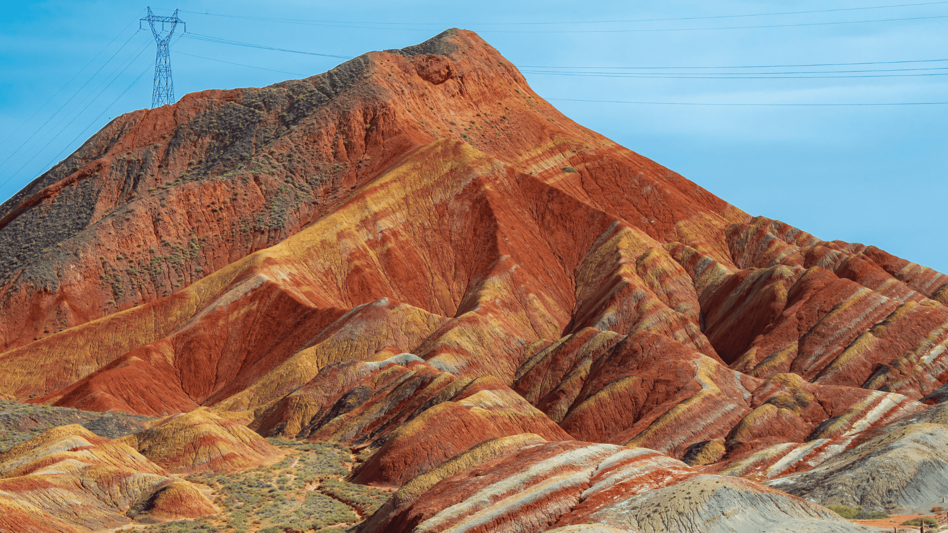 ภูเขาหลากสี Zhangye Danxia ในจีน แสดงลวดลายสีแดง เหลือง และส้มสลับชั้นกันอย่างชัดเจนบนผิวภูเขา