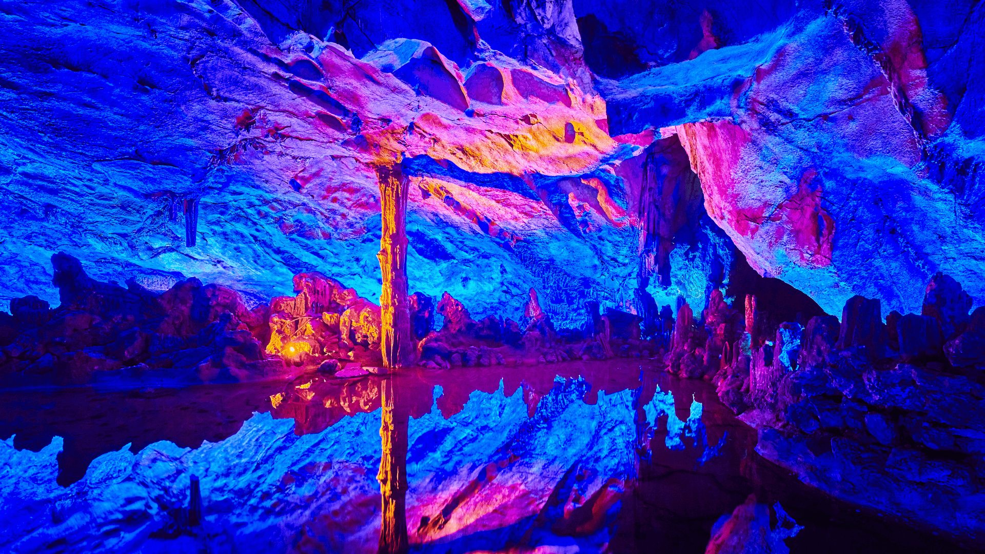 ถ้ำหินงอกหินย้อยเรืองแสงหลายสีจากไฟประดับใน Reed Flute Cave ทำให้ผนังถ้ำสะท้อนสีฟ้า ชมพู และม่วงอย่างงดงาม
