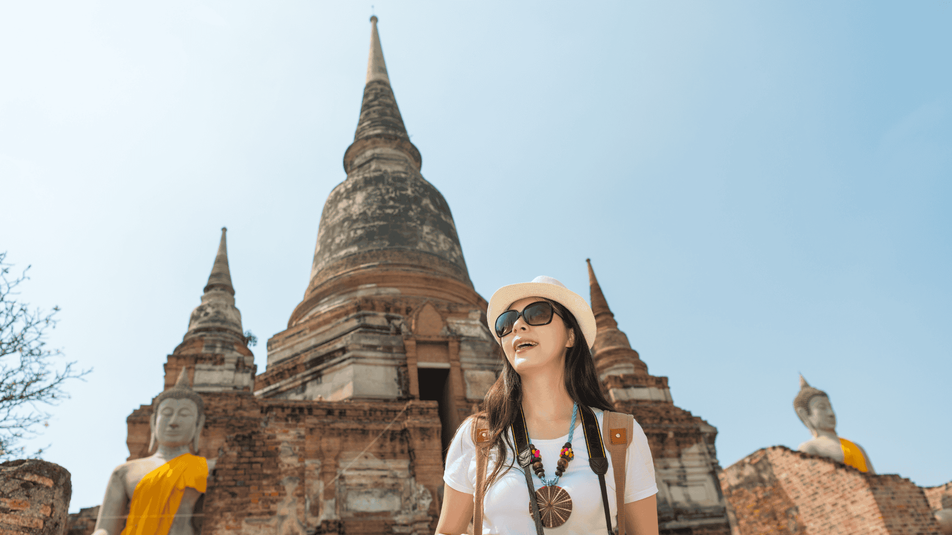 นักท่องเที่ยวเดินชมโบราณสถานเจดีย์และพระพุทธรูปในอุทยานประวัติศาสตร์อยุธยา ท่ามกลางท้องฟ้าใส