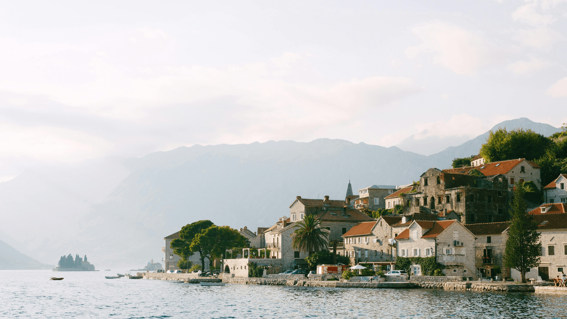 Coastal town in Montenegro with red rooftops along a mountain bay.