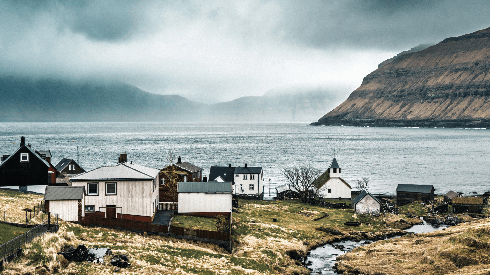 Seaside village in the Faroe Islands with cliffs and misty weather.