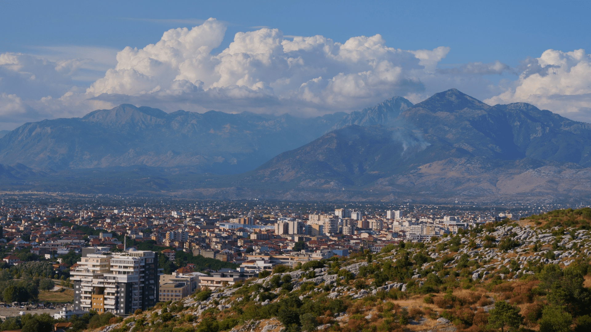 City view in Albania with urban buildings set against mountain scenery-min