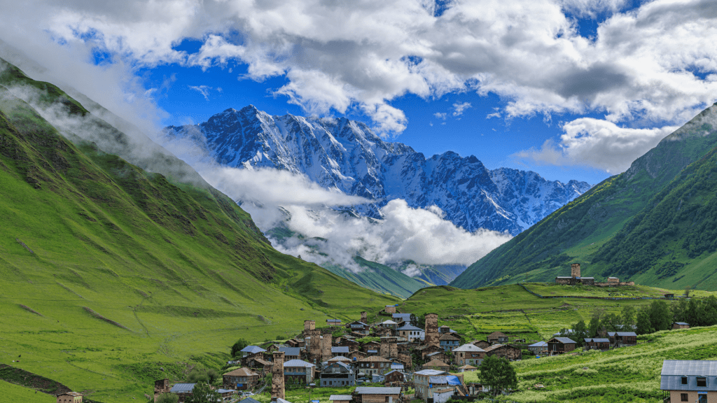 Mountain village in Georgia with green valleys and snow-capped Caucasus Mountains