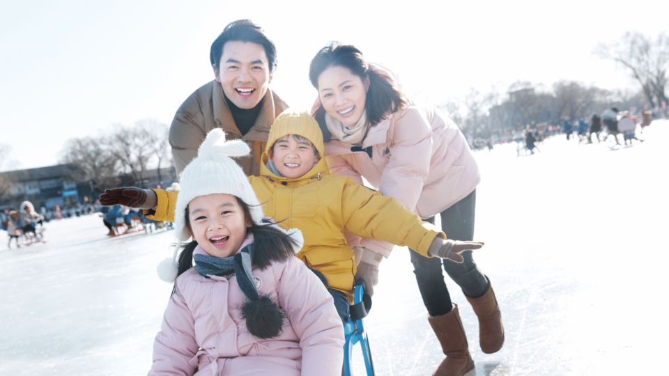 Happy Asian family enjoying winter activities together on a snowy day