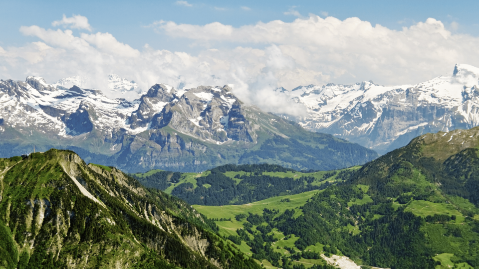 Panoramic view of the European Alps with green valleys and dramatic mountain peaks