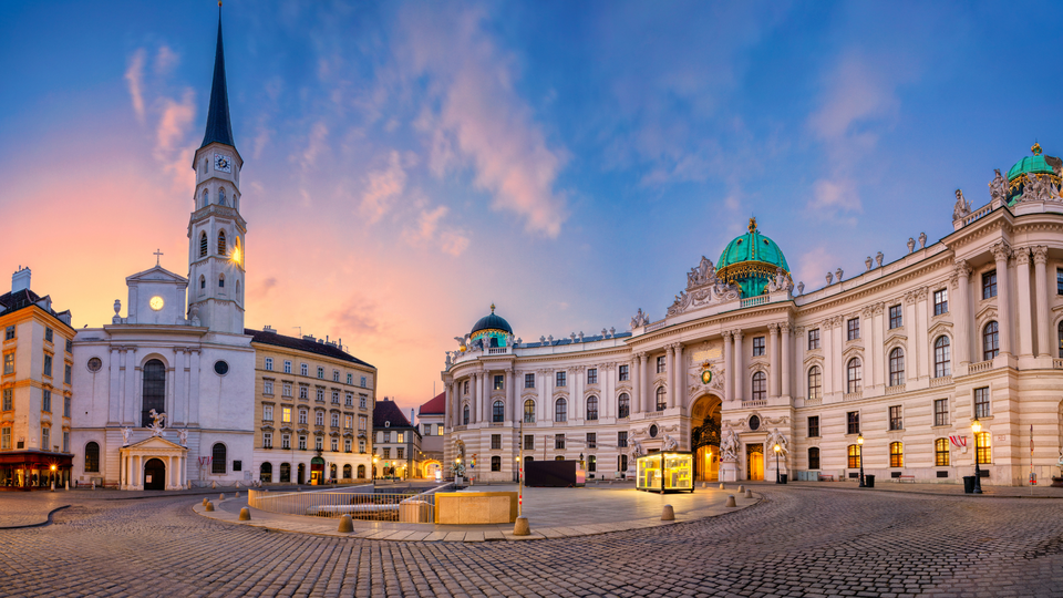 Hofburg Palace in Vienna at sunset, showcasing elegant historic architecture and an open square with soft evening light.