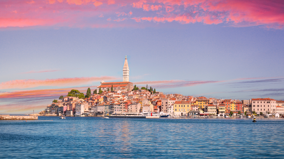 Colorful coastal town in Europe at sunset with calm sea and pastel sky, perfect for a relaxed March city break.