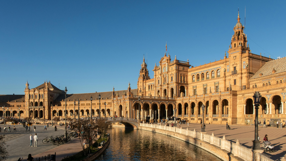 Plaza de España in Seville with historic arches, canal, and decorative bridge in Andalusia, Spain.