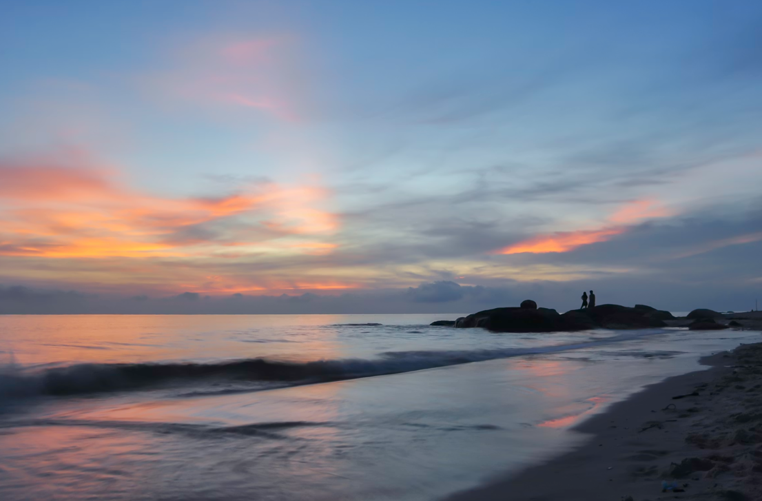 Beachfront infinity pool overlooking Hua Hin Beach with lounge chairs, umbrellas, and the Gulf of Thailand in the background.