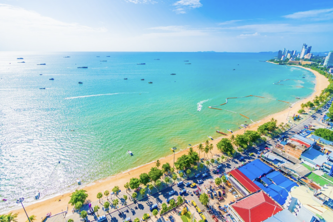 Beachfront café seating with white tables and chairs on the sand overlooking the sea in Hua Hin, Thailand, with string lights and coastal views.